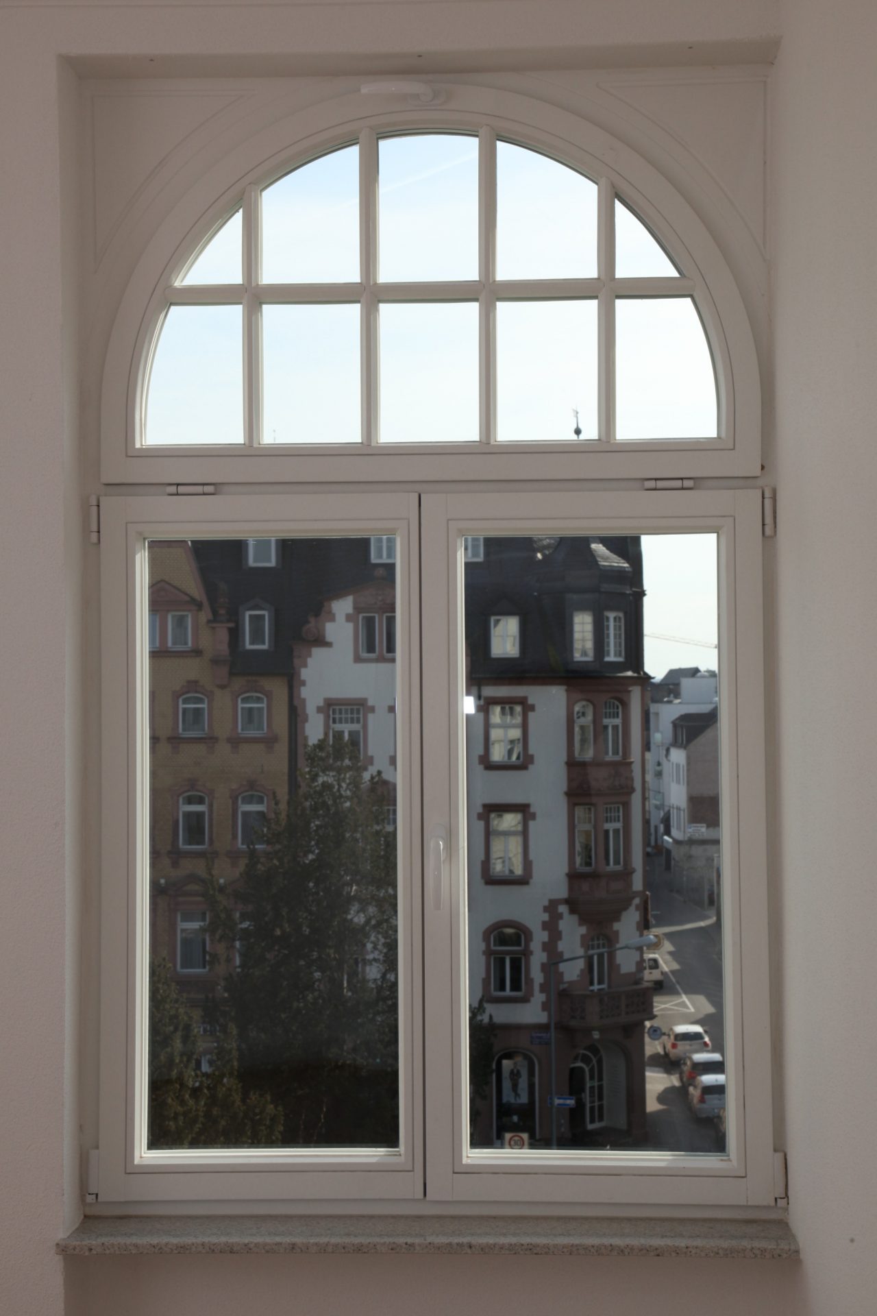 Modernes weißes Holzfenster mit Rundbogen in denkmalgeschütztem Gebäude