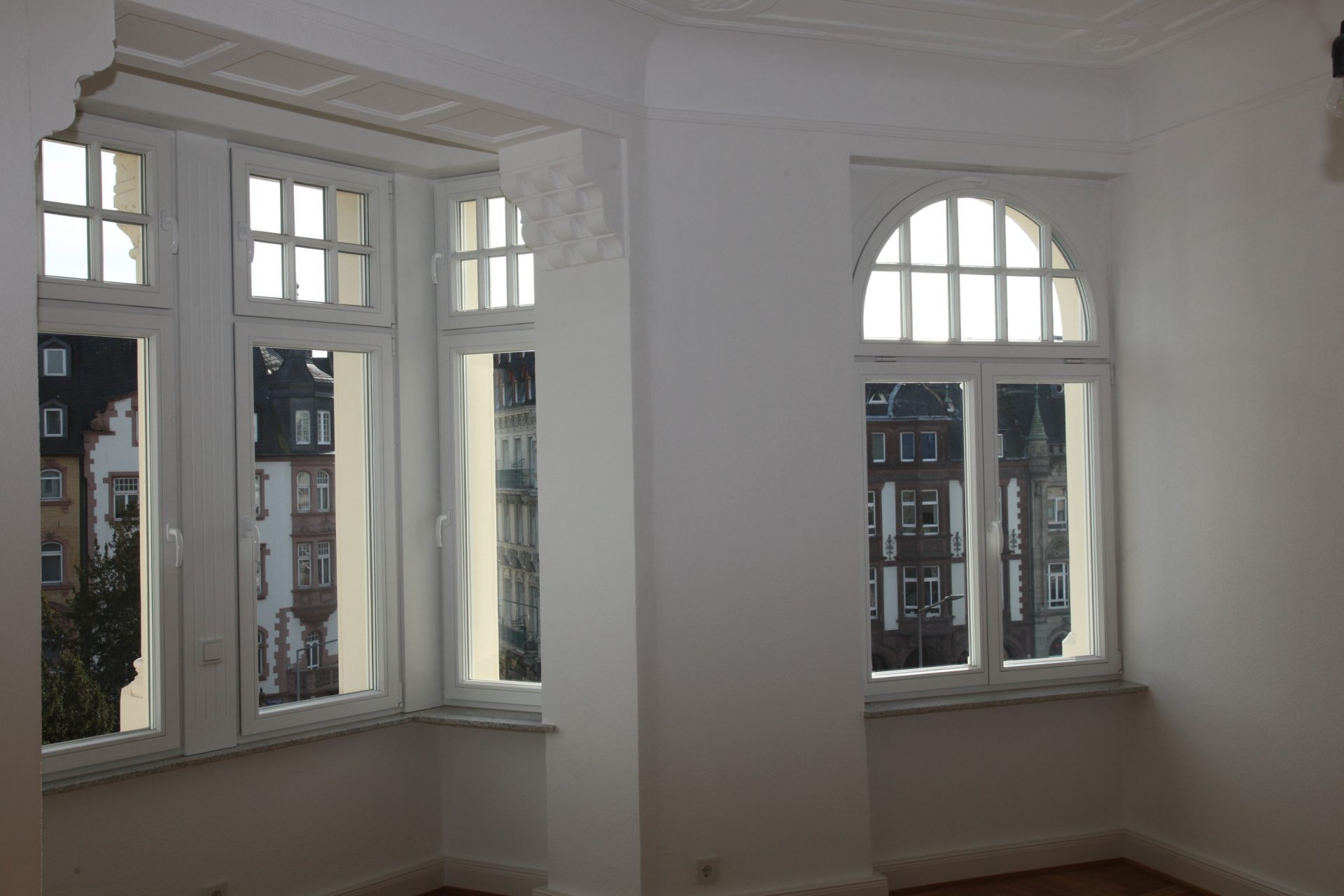Modernes weißes Holzfenster mit Rundbogen in denkmalgeschütztem Gebäude